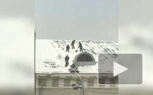 В Москве дворники, скатываясь без страховки, синхронно чистили крыши от снега