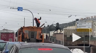 Коммунальщик сбрасывал песок на тротуар, находясь в кузове грузовика, на набережной Фонтанки